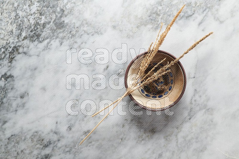 Wheat stalks on Decorative Pottery Plate on grey marble flooring, Top view