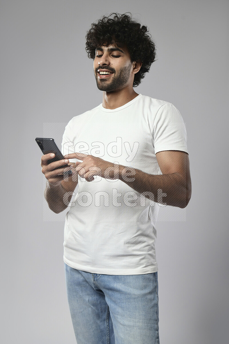 A man wearing casual standing and browsing on the phone on white background