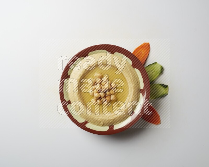 Hummus in a traditional plate garnished with roasted chickpeas  on a white background