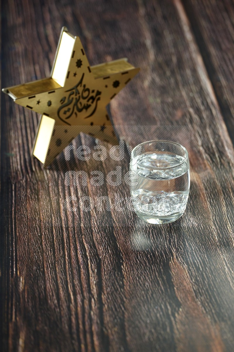 A star lantern with drinks, dates, nuts, prayer beads and quran on brown wooden background