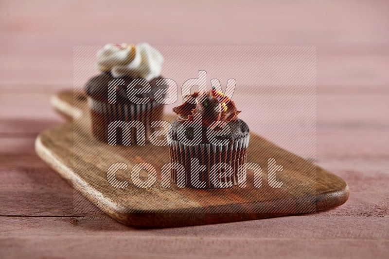 Chocolate mini cupcake topped with chocolate cream on a wooden board
