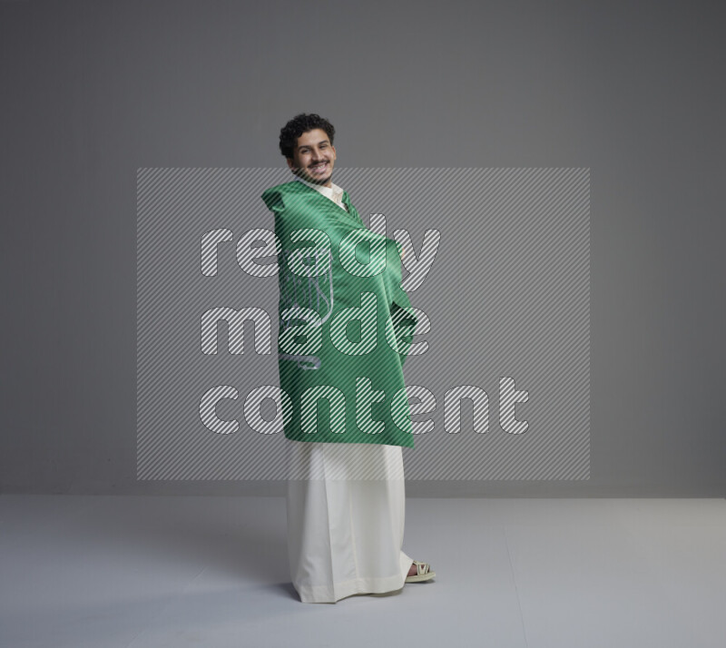 رجل سعودي يرتدي ثوب ابيض ويحمل علم السعودية