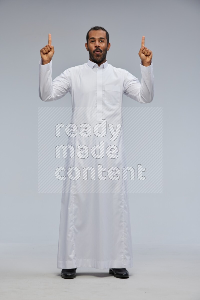 Saudi man Wearing Thob standing interacting with the camera on Gray background