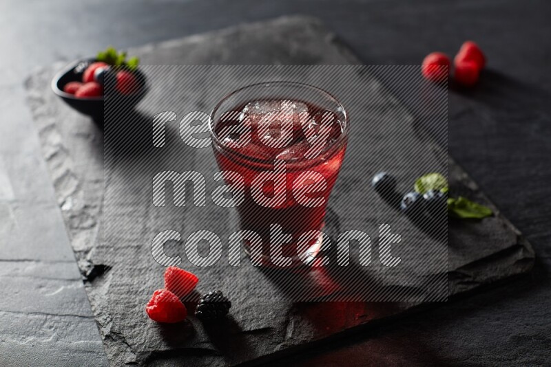 A glass of mixed berries juice on black background