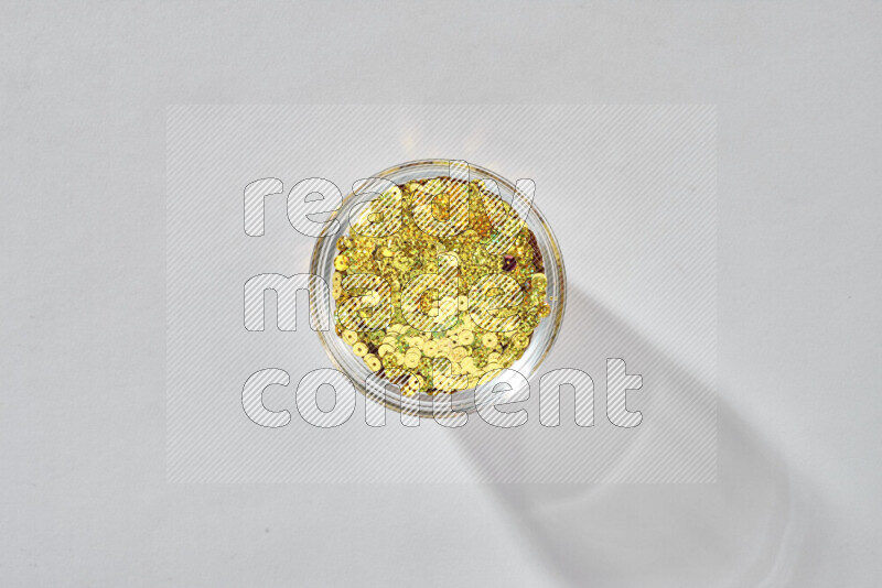 Colored flat sequins in a glass bowl on grey background