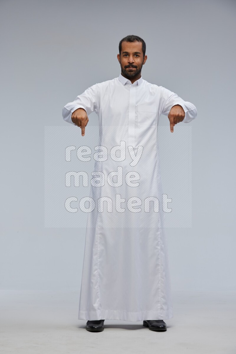 Saudi man Wearing Thob standing interacting with the camera on Gray background