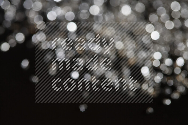 Silver shimmering fragments of glass scattered on a black background