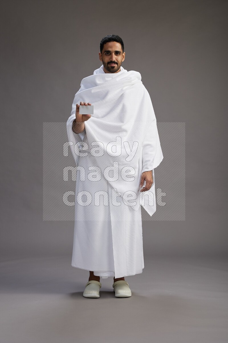 A man wearing Ehram Standing holding ATM card on gray background