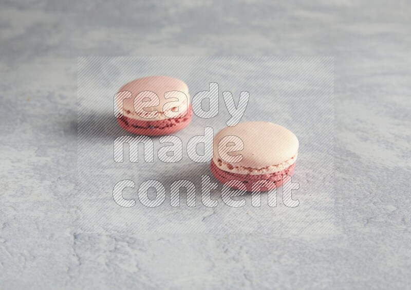 45º Shot of two Pink Litchi Raspberry macarons  on white  marble background