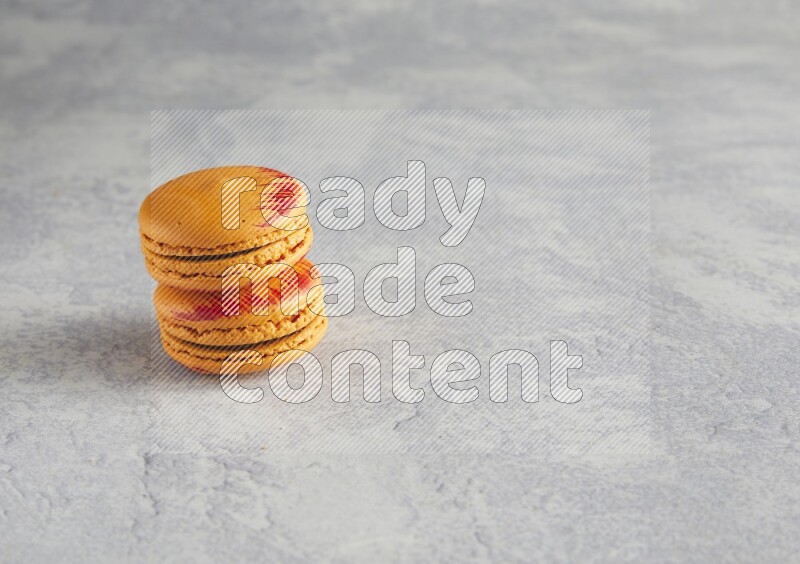 45º Shot of two orange Exotic macarons on white  marble background