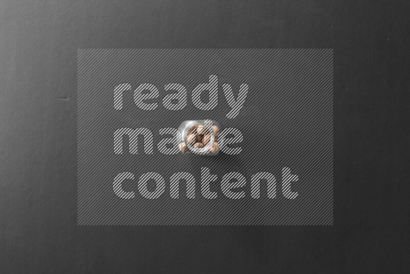 A glass spice jar full of nutmeg on black flooring