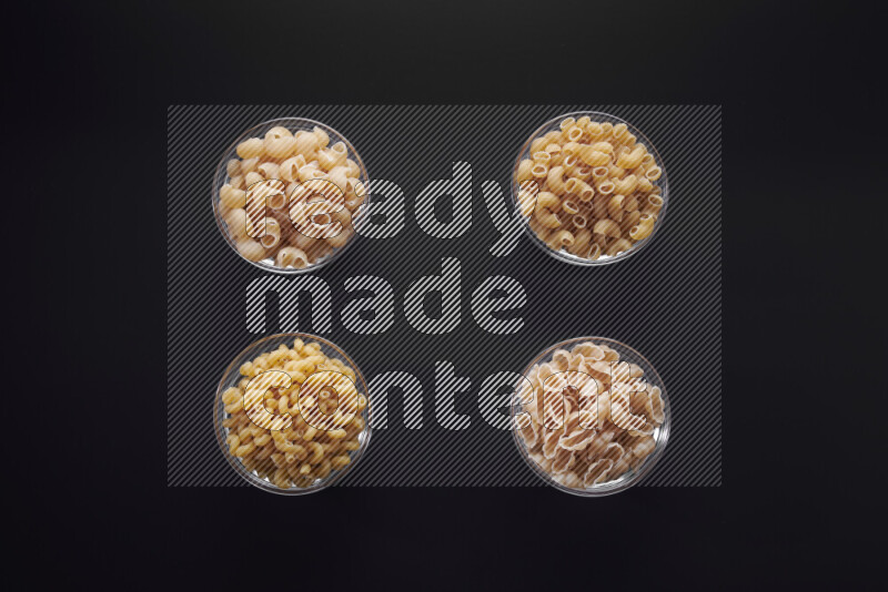 أنواع مختلفة من المعكرونة في وعاء زجاجي علي خلفية سوداء