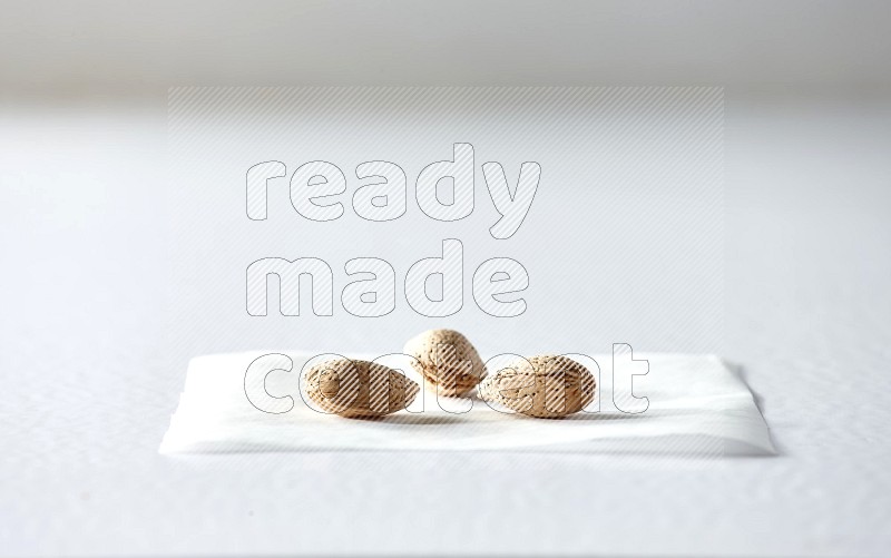 3 almonds on a piece of paper on a white background in different angles