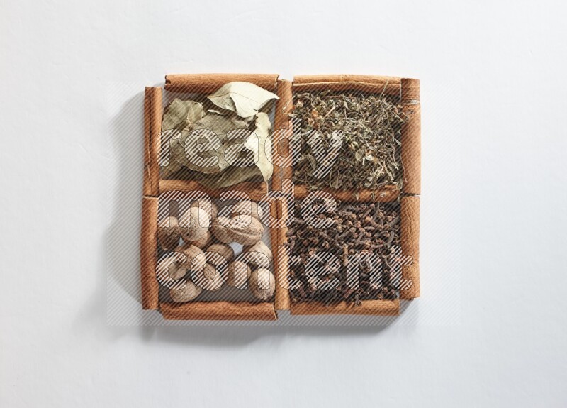 4 squares of cinnamon sticks full of bay laurel leaves, dried basil, cloves and nutmegs on white flooring