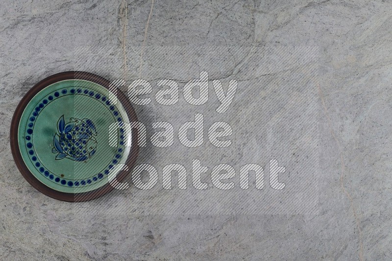 Top View Shot Of A Decorative Pottery Plate On Grey Marble Flooring