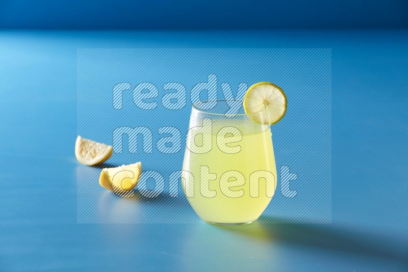 glass of lemon juice with lemon slice  on blue background