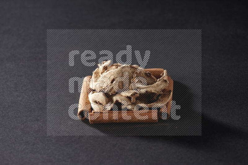 A single square of cinnamon sticks full of dried ginger on black flooring