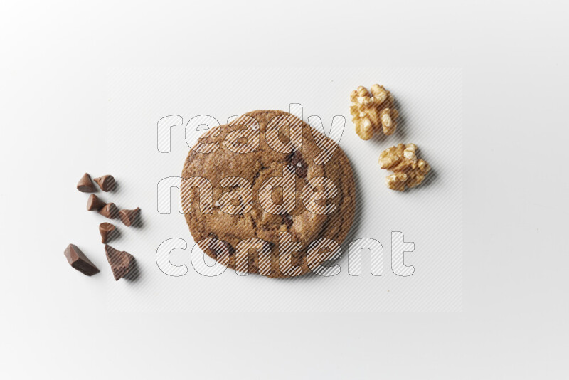 A single chocolate chips cookie with chocolate and walnuts beside it on a white background