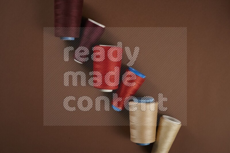 مجموعة من أدوات الخياطة والتفصيل حمراء اللون على خلفية بنية