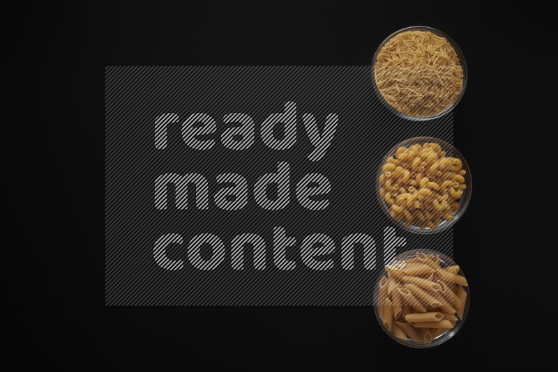 Different pasta types in 3 glass bowls on black background