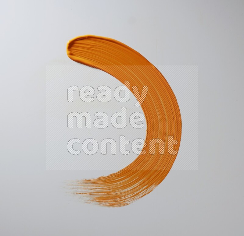 An orange half circular painting brush stroke on white background