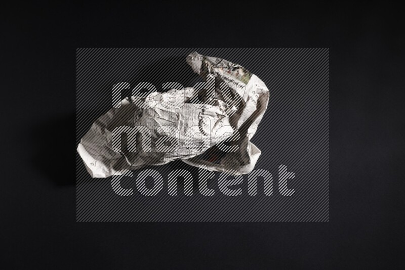 Crumpled newspaper sheet on black background