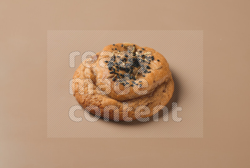 a whole Hasawi cookie with grains on a brown background
