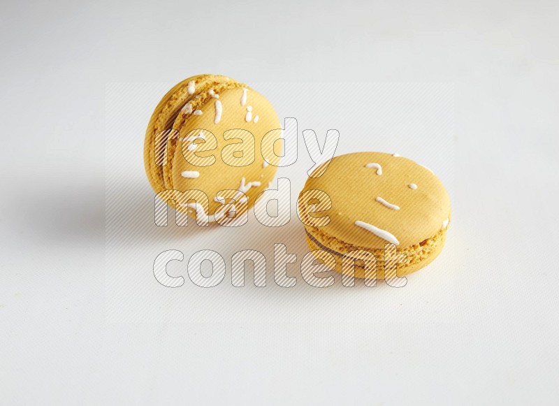 45º Shot of two Yellow Piña Colada macarons on white background