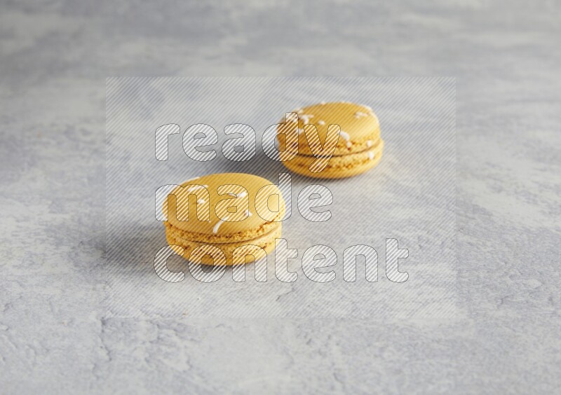 45º Shot of two Yellow Piña Colada macarons  on white  marble background