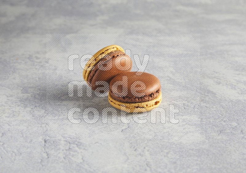 45º Shot of two Yellow and Brown Chai Latte macarons r on white  marble background