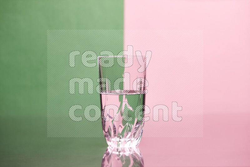 The image features a clear glassware filled with water, set against green and rose background