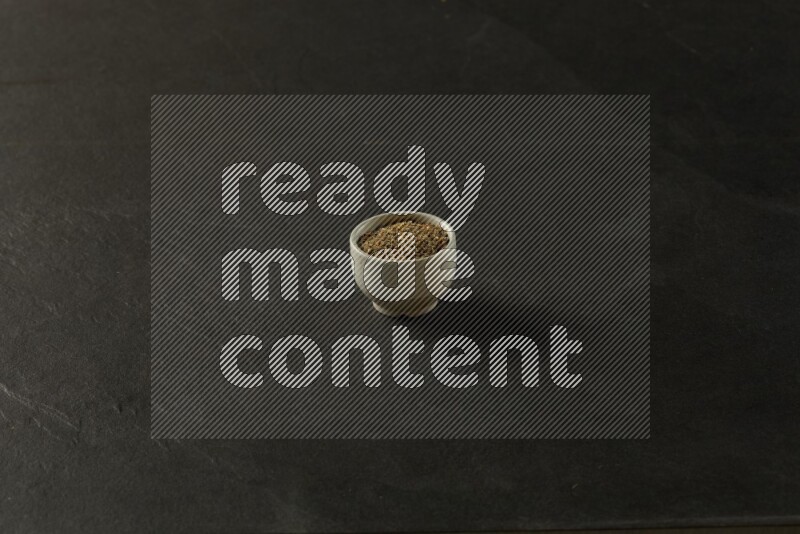 white ceramic round sauce bowl filled with herbs on grey textured countertop