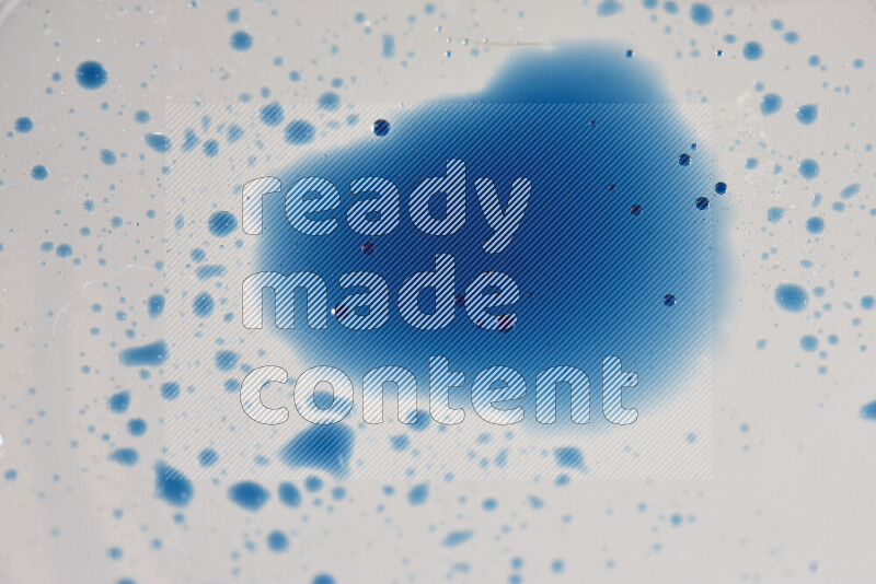 لقطات مقربة لقطرات ألوان مائية زرقاء على سطح الزيت على خلفية بيضاء