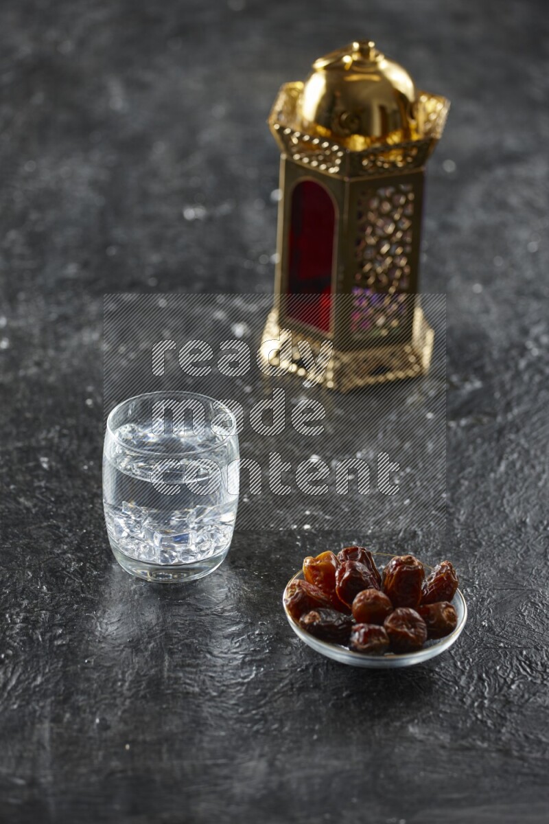 A golden lantern with different drinks, dates, nuts, prayer beads and quran on textured black background