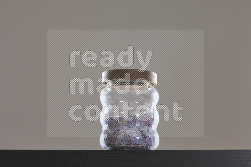 Sequins in a glass jar on black background