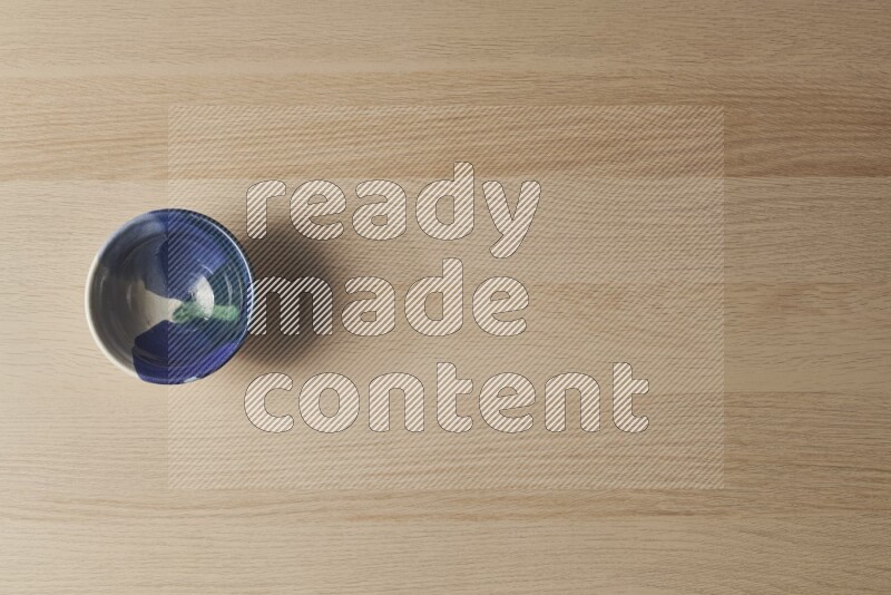A multicolored pottery bowl on light wooden background