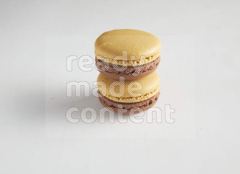 45º Shot of two Yellow and Brown Chai Latte macarons on white background