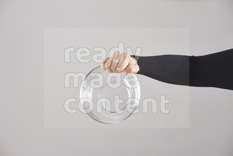 A woman in black abaya holding different glassware in different positions