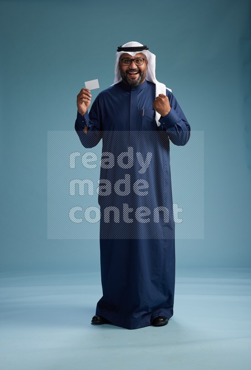 Saudi Man with shimag Standing holding ATM on blue background