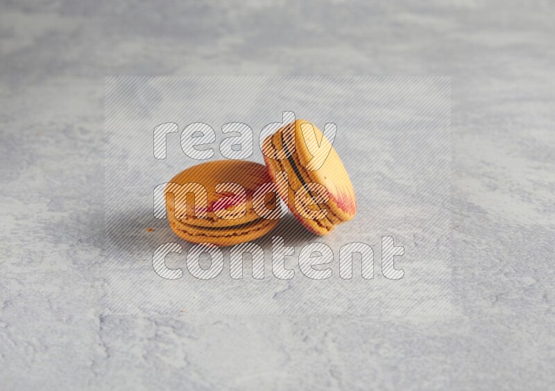 45º Shot of two orange Exotic macarons on white  marble background