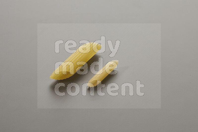 Penne pasta with other types of pasta on grey background