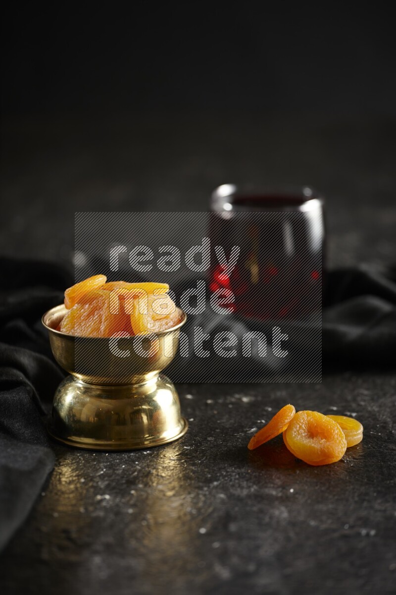Dried fruits in a metal bowl with Hibiscus and a napkin in a dark setup