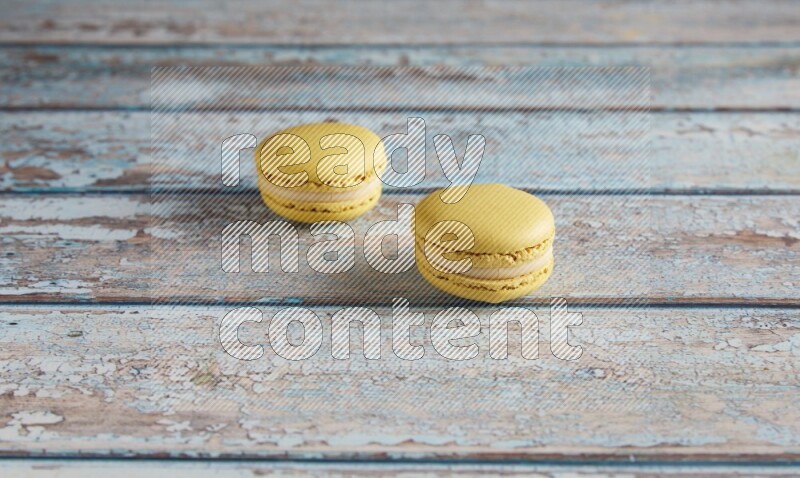 45º Shot of two Yellow Lime macarons on light blue wooden background