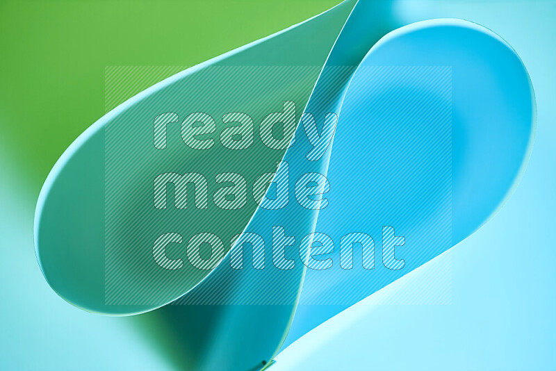 An abstract art of paper folded into smooth curves in green and blue gradients