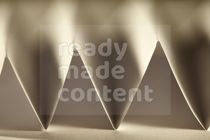 صورة مجردة مقربة تظهر طيات ورقية هندسية حادة بتدرجات الوان دافئة