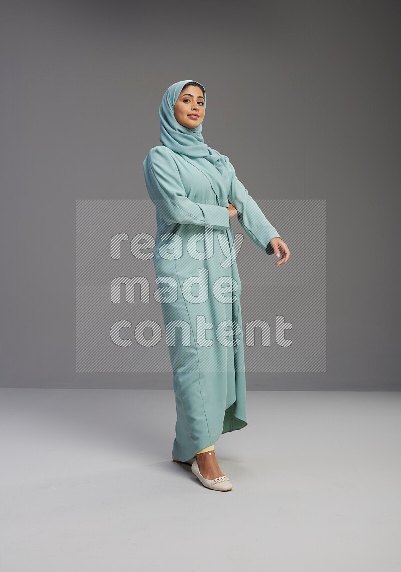 Saudi Woman wearing Abaya standing interacting with the camera on Gray background