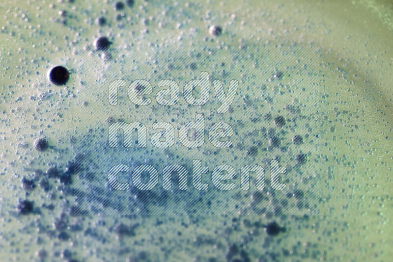 لقطات مقربة لقطرات ألوان مائية زرقاء على سطح الزيت على خلفية خضراء