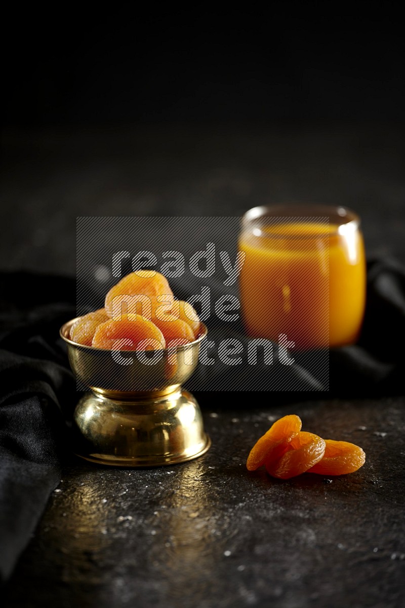 Dried fruits in a metal bowl with qamar eldin and a napkin in a dark setup