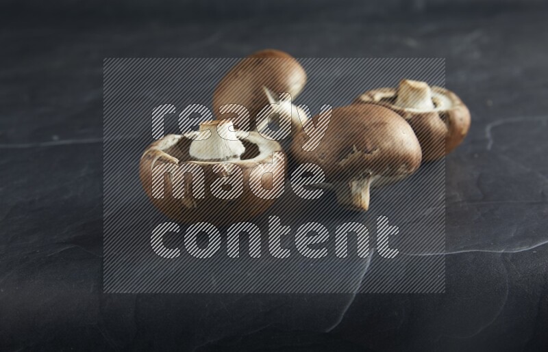 45 degre cremini  mushrooms on a textured black slate background