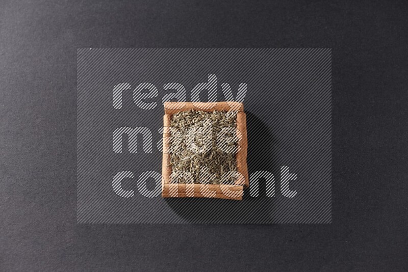 A single square of cinnamon sticks full of cumin on black flooring
